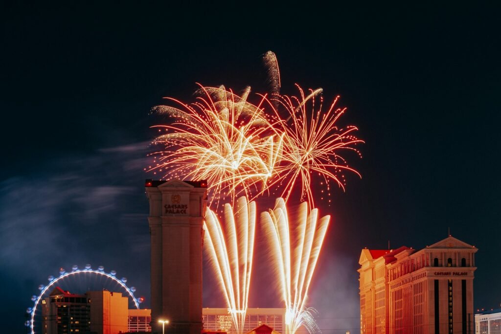 Fireworks explode above city buildings at night.