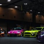 Colorful customized cars displayed under exhibition lights; illustrative photograph, not SEMA 2026