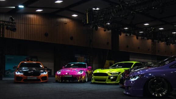 Colorful customized cars displayed under exhibition lights; illustrative photograph, not SEMA 2026